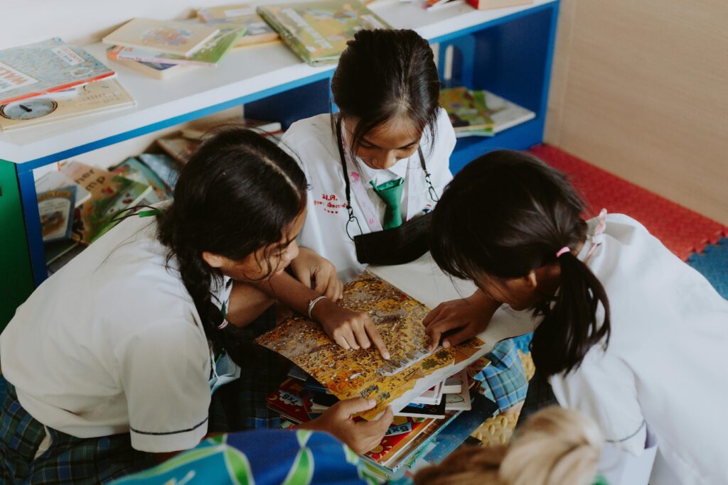 Group of children engaging in collaborative learning in a school setting, focused on a book.