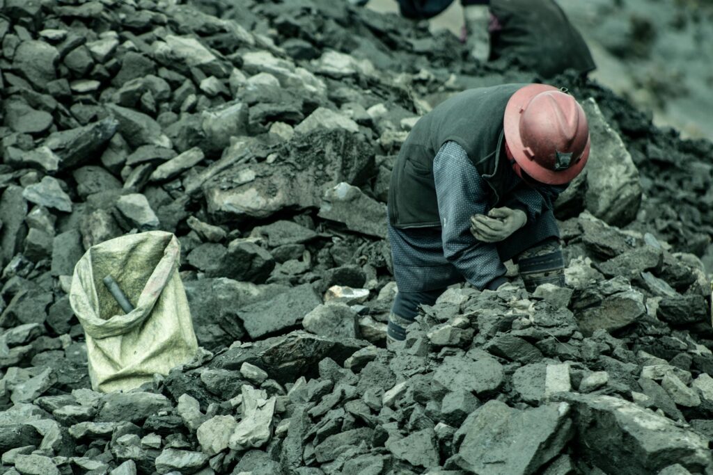 A woman mining for gold in La Rinconada, Peru, surrounded by rocks and debris.