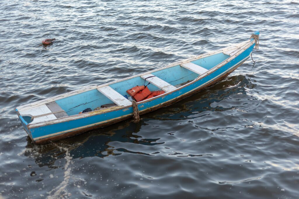A lone blue boat floats serenely on the ocean near Arraial d'Ajuda, Bahia, Brasil.