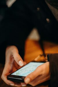 Close-up of hands using a smartphone for map navigation indoors.