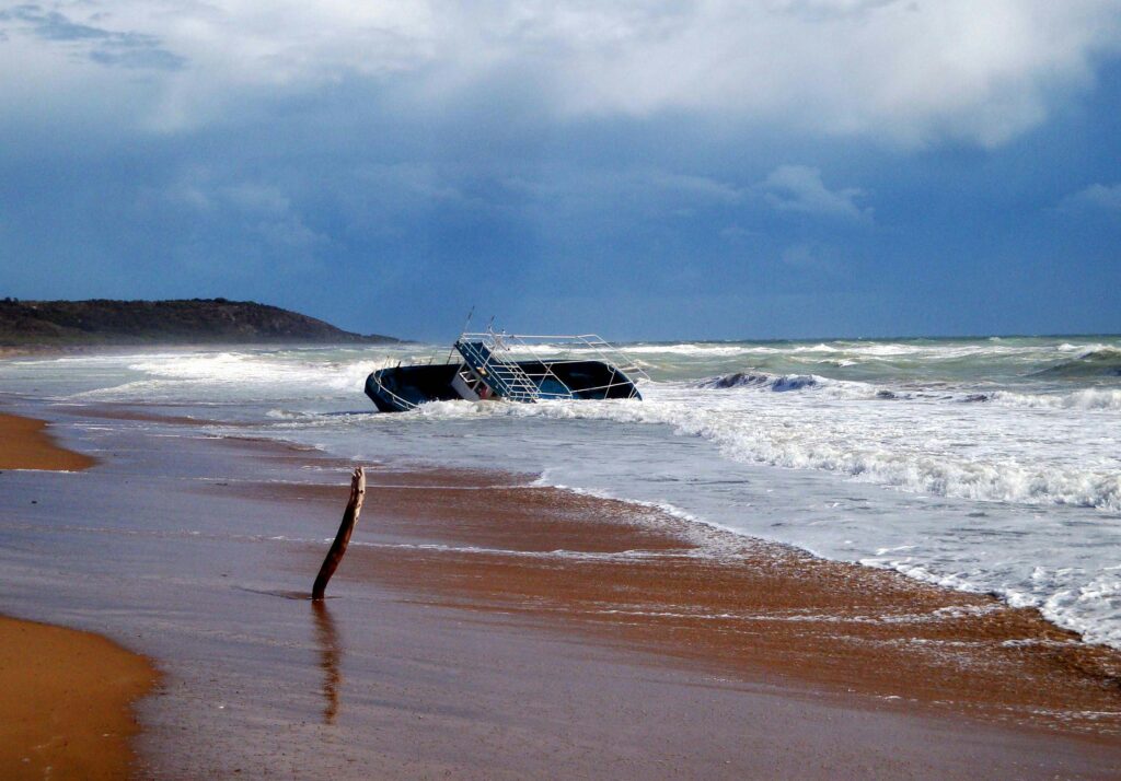 Dramatic view of a shipwreck on a stormy Sicilian beach, showcasing the power of nature.