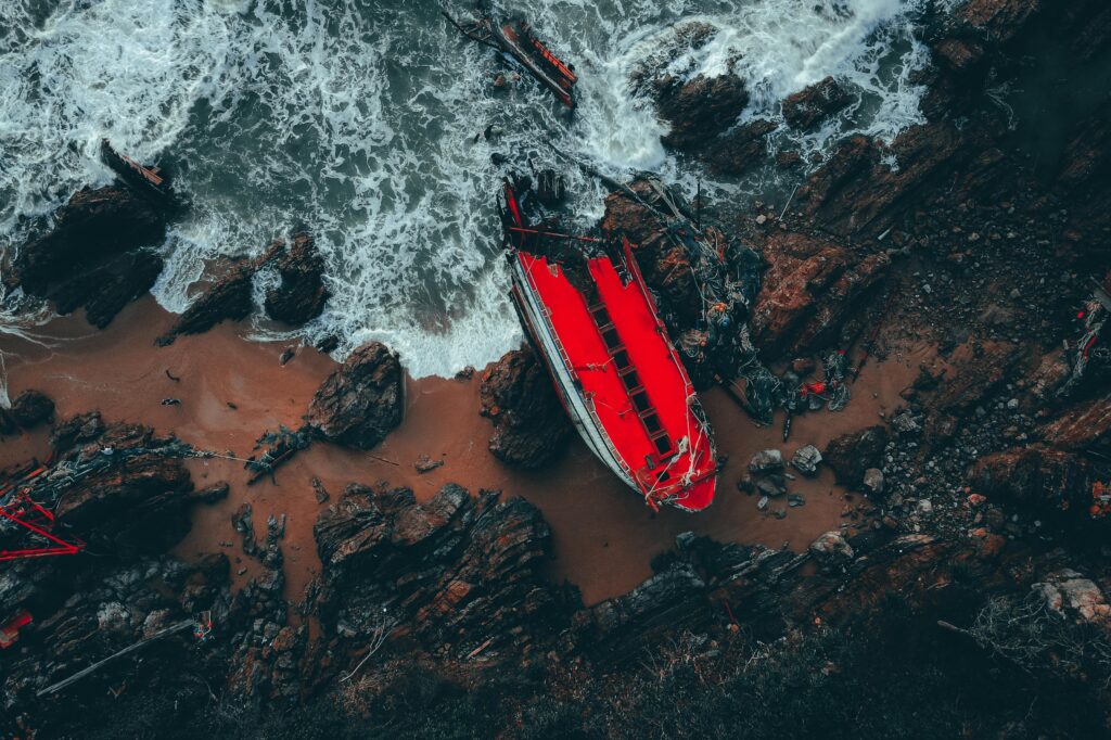 Dramatic aerial shot of a shipwreck on Kemaman's rocky shoreline in Malaysia.